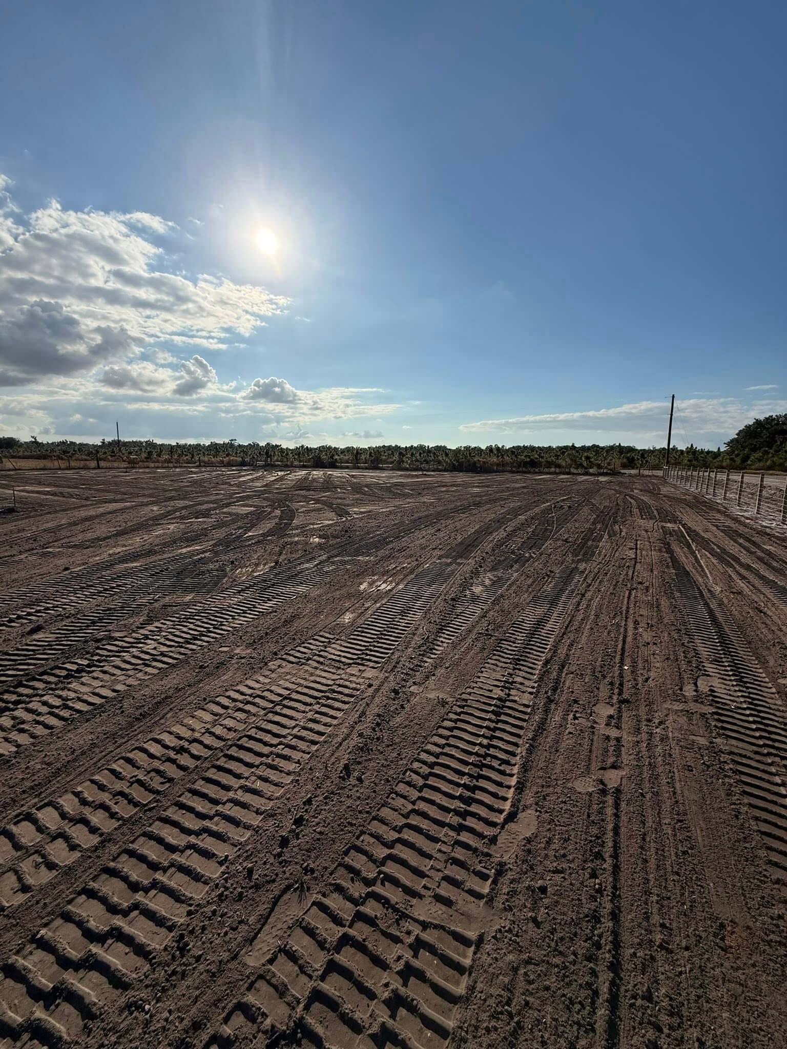 Precision graded field with tire track patterns at sunset