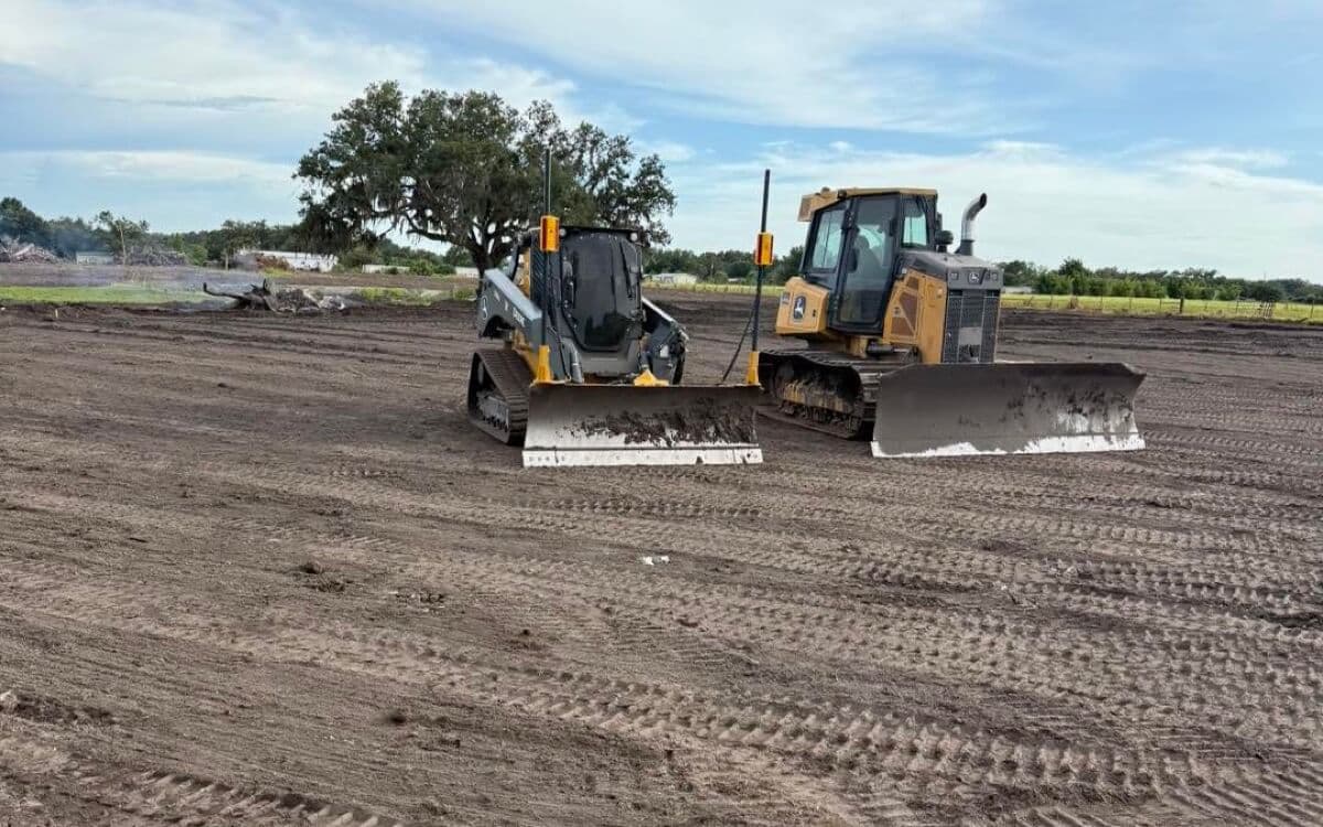 Bulldozer and skid steer performing precision land grading